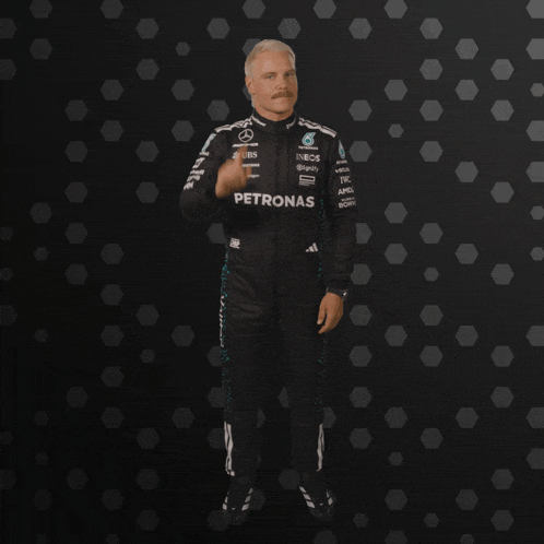 a man in a petronas suit stands in front of a black background