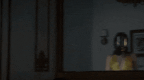 a woman in a yellow tank top is standing in front of a mirror