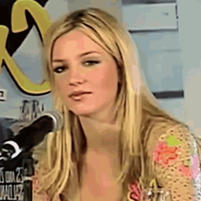 a woman with long blonde hair is sitting in front of a microphone .