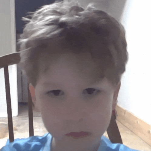 a young boy in a blue shirt is sitting in a rocking chair