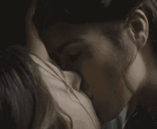 a woman is kissing another woman on the forehead in a dark room .