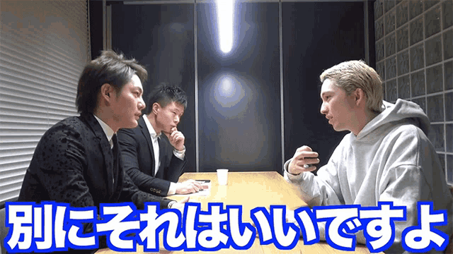 three men are sitting at a table in a dark room with chinese writing on it