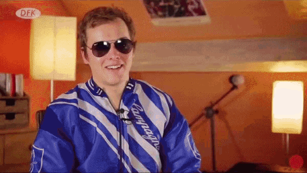 a man wearing sunglasses and a blue jacket with campagnolo on it