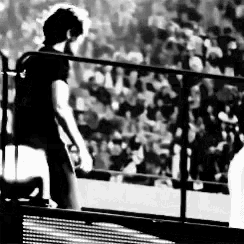 a black and white photo of a man walking across a stage .