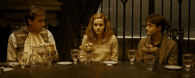 three people sit at a table with plates of food