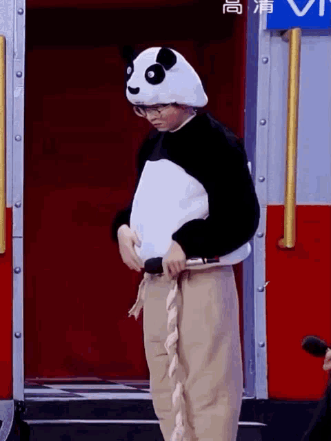 a person dressed in a panda costume is standing in front of a red door