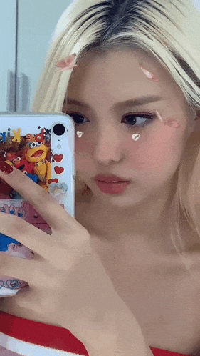 a woman is taking a picture of herself in a mirror with sesame street stickers on her face