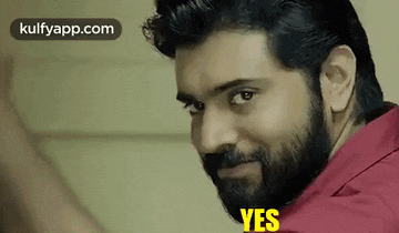 a man with a beard and a red shirt is making a funny face .