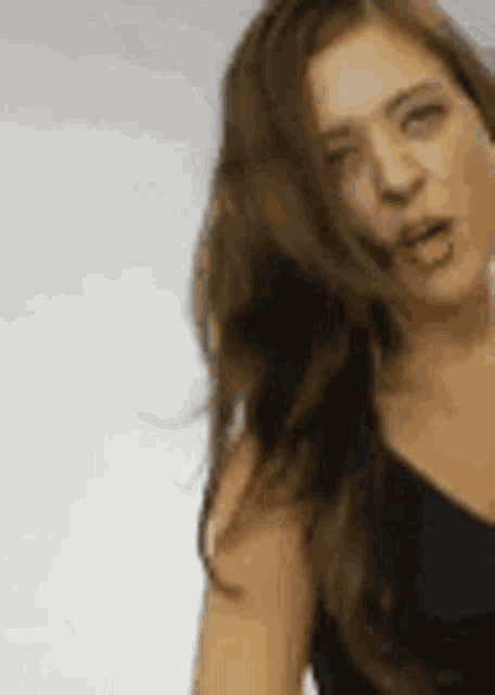 a woman with long hair is wearing a black dress and making a face .