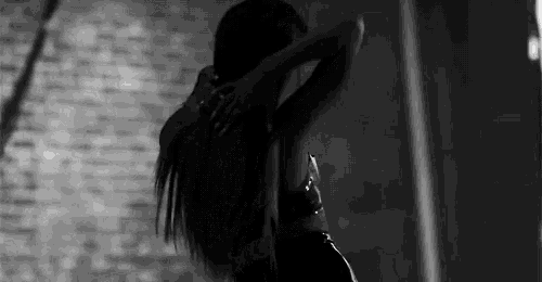 a black and white photo of a woman dancing in a room .