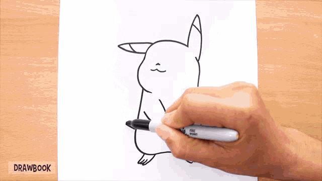 a person is drawing a pikachu on a piece of paper with a sharpie marker