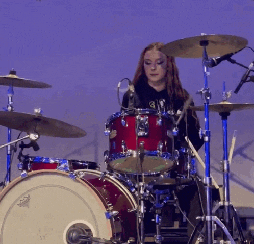 a woman is playing a drum set with a remo drum head