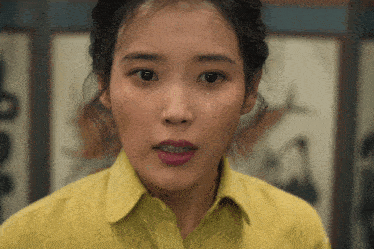 a woman in a yellow shirt has a tear running down her cheek