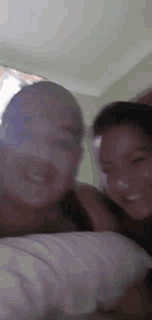 a man and a woman are laying on a bed smiling at the camera .