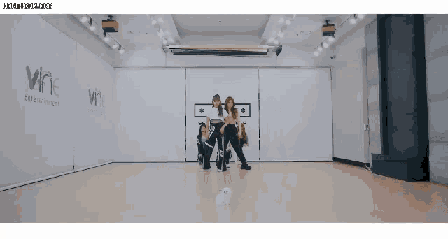 a group of women are dancing in a dance studio with the word wine on the wall .