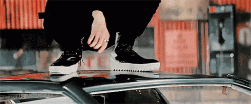 a person is squatting on top of a car .