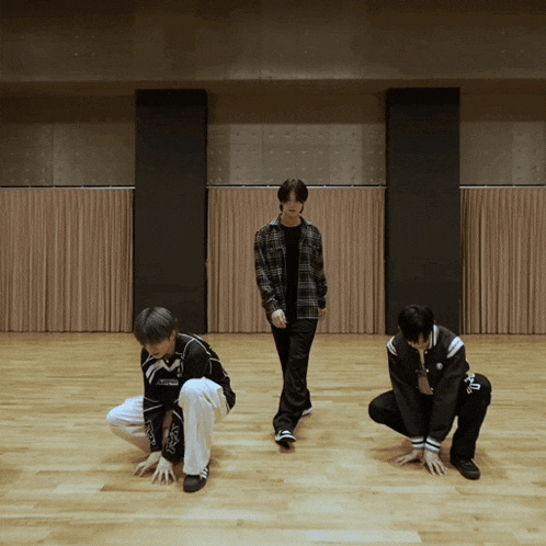 a group of young men are dancing in a room and one of them is wearing a shirt that says ' x '