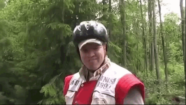 a man wearing a helmet is standing in the woods .