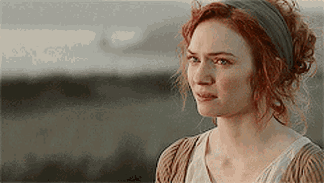a woman with red hair is wearing a headband and looking at something