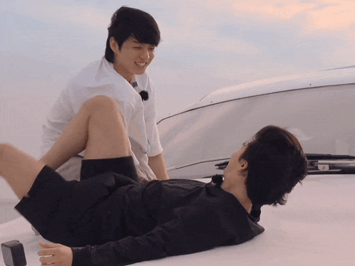 a man laying on another man 's lap with a white shirt on