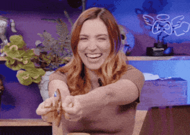 a woman is laughing in front of a neon sign that says ' angels '