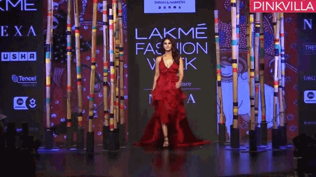 a woman in a red dress is walking down the runway at a lakme fashion week event