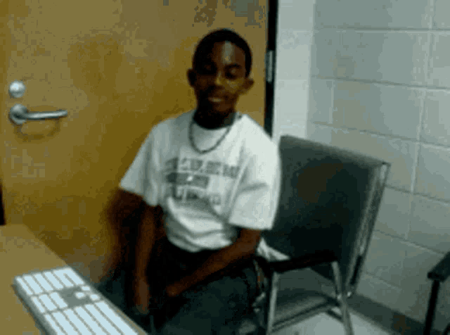 a young man wearing a shirt that says u.s. army is sitting in front of a computer keyboard