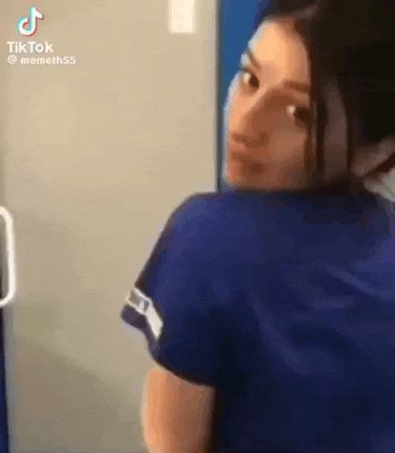 a woman in a blue shirt is standing next to a door .