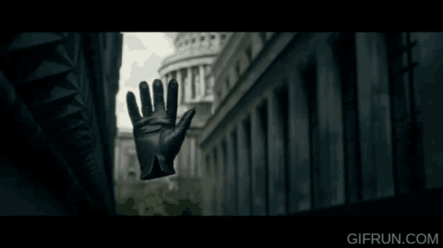 a hand in a black leather glove is reaching out towards a building with a gifrun.com logo in the corner
