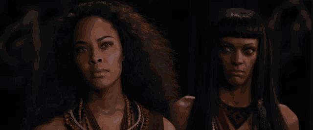 two women are standing next to each other in the dark