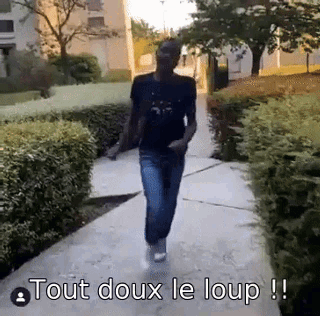 a man walking down a sidewalk with the words tout doux le loup