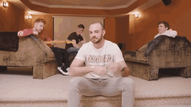 a man wearing a t-shirt that says ' hendrix ' on it sits on a couch