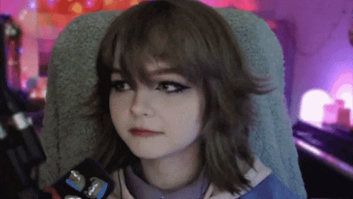 a girl with short hair is sitting in a chair with a microphone in front of her .