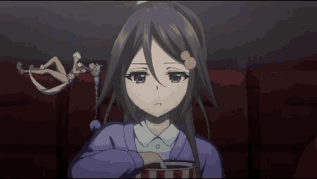 a girl in a purple sweater is eating popcorn