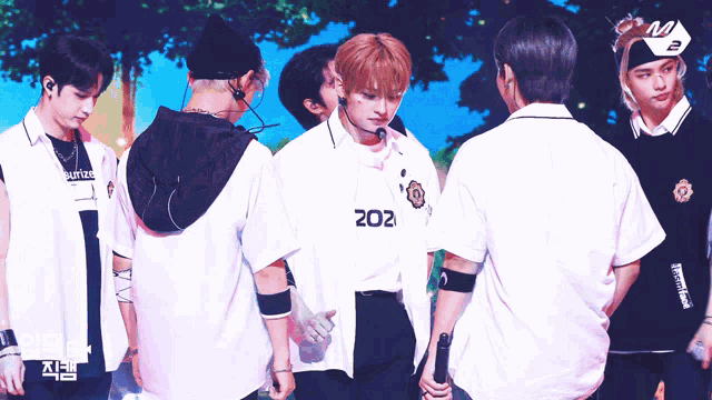 a group of young men are standing in a line with one wearing a shirt with the number 202 on it