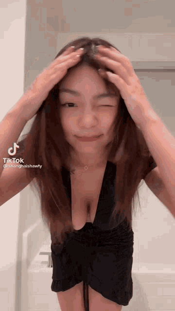 a woman in a black dress with a very plunging neckline is standing in front of a bathtub .