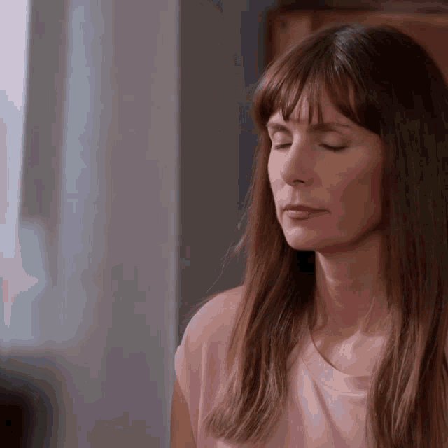 a woman with her eyes closed is wearing a pink t-shirt