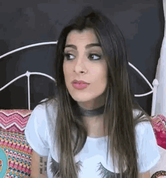 a woman is sitting on a bed wearing a choker .