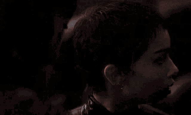 a close up of a man in a batman mask kissing a woman on the forehead .