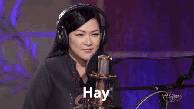 a woman wearing headphones is singing into a microphone with the word day written on it .