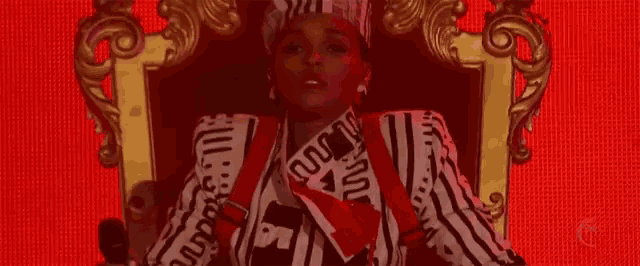 a woman in a striped jacket is sitting on a throne with a red background