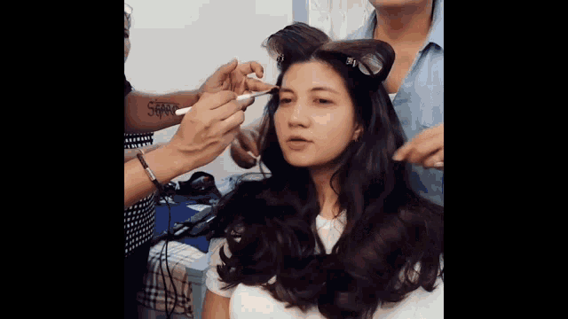 a woman is getting her hair done by a woman with a tattoo on her arm that says ' sss '