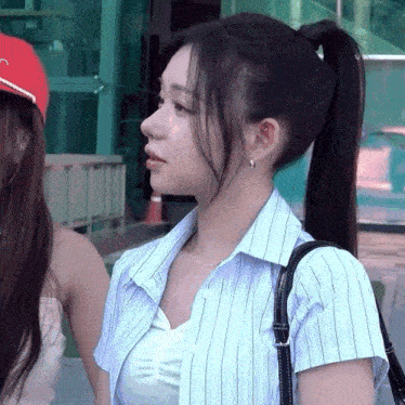 a woman with a ponytail is wearing a blue striped shirt