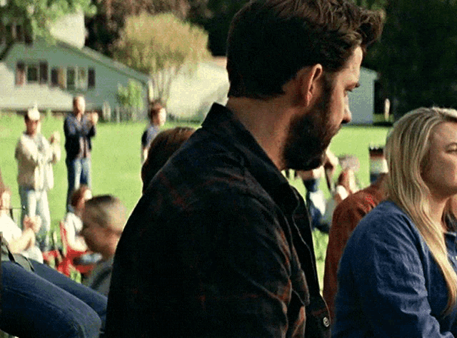 a man in a plaid shirt stands in front of a crowd