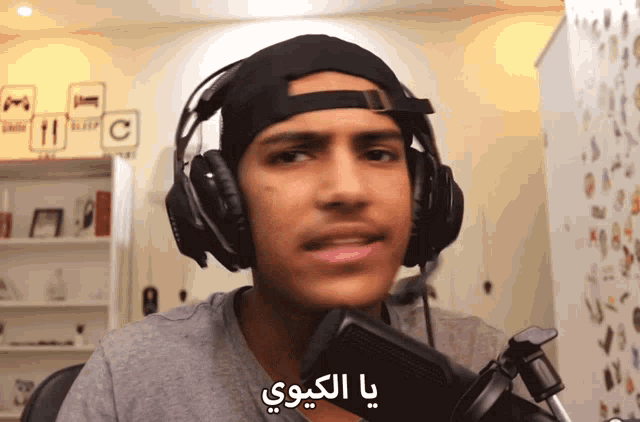 a man wearing headphones and a baseball cap says " ya alkoo "