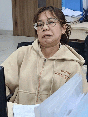 a woman sitting at a desk wearing a hoodie that says bambotude