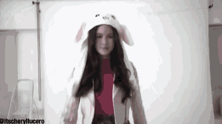 a woman wearing a pink turtleneck and a white hat with bunny ears .