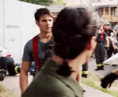 a man and a woman are standing next to each other on a sidewalk and the man is wearing a firefighter 's uniform