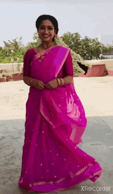 a woman is wearing a pink saree and smiling