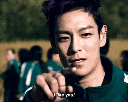 a man with purple hair is pointing at the camera and says i like you